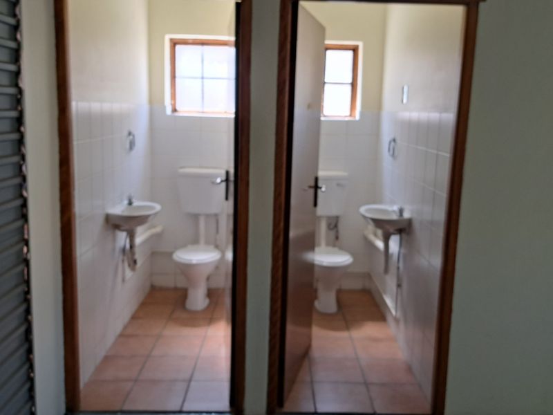 Two separate, functional office restrooms featuring tiled flooring, wall-mounted basins, and close-coupled toilets.