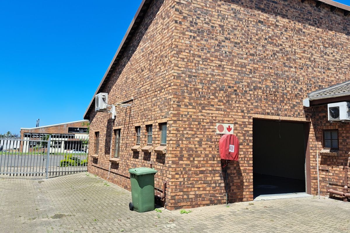 Exterior view of a face brick office building featuring a paved driveway, fire safety equipment, and external air conditioning units.