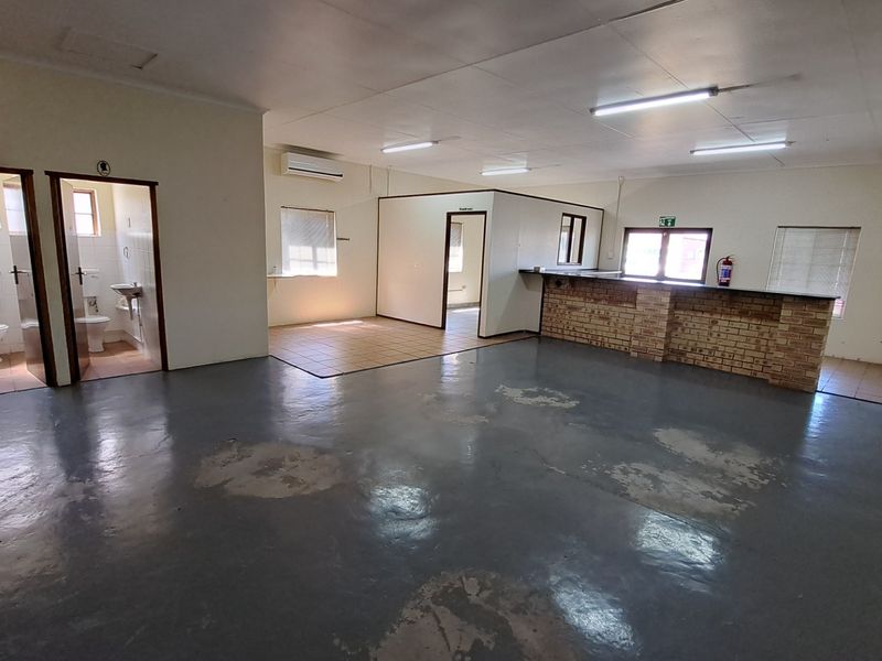 Spacious open-plan office area featuring a brick service counter, two private restrooms, and split-system air conditioning, offering a versatile layout for business operations.