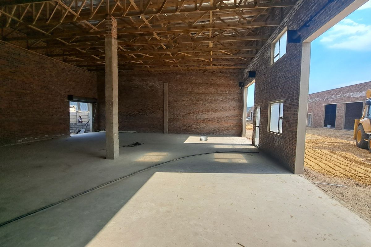Spacious industrial utility area featuring exposed brick walls, concrete flooring, and open timber roof trusses, currently in an unfinished construction state.