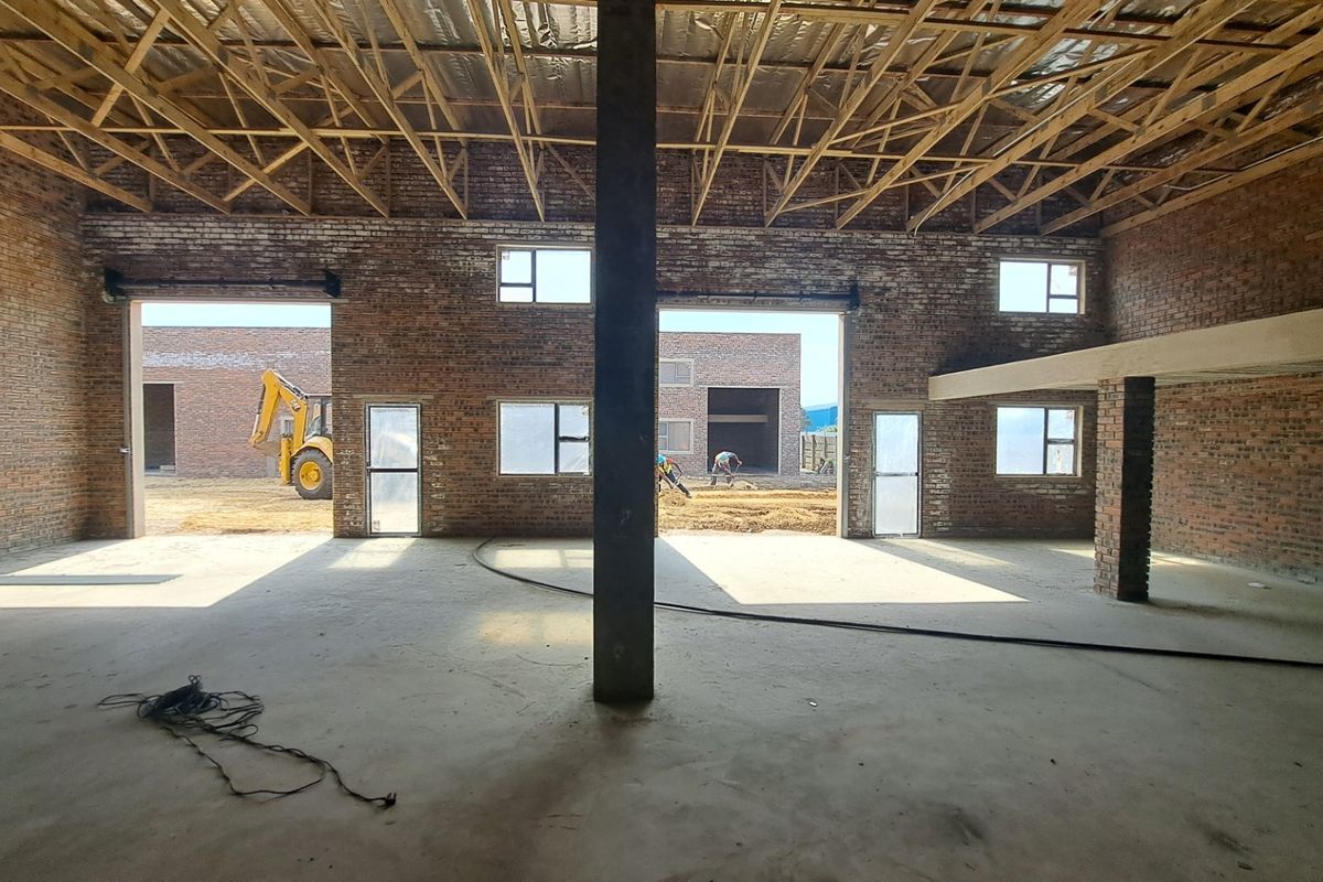 Spacious industrial open-plan area under construction, featuring exposed brick walls, timber roof trusses, and a mezzanine level with large openings to the exterior.
