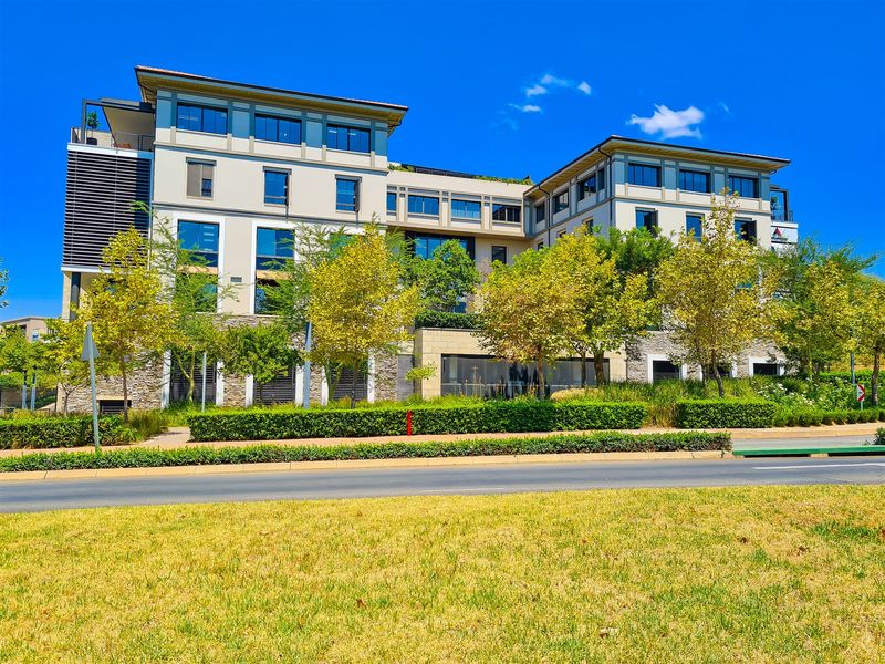 A modern multi-story office building featuring stone cladding, large glass windows, and well-maintained landscaped surroundings.