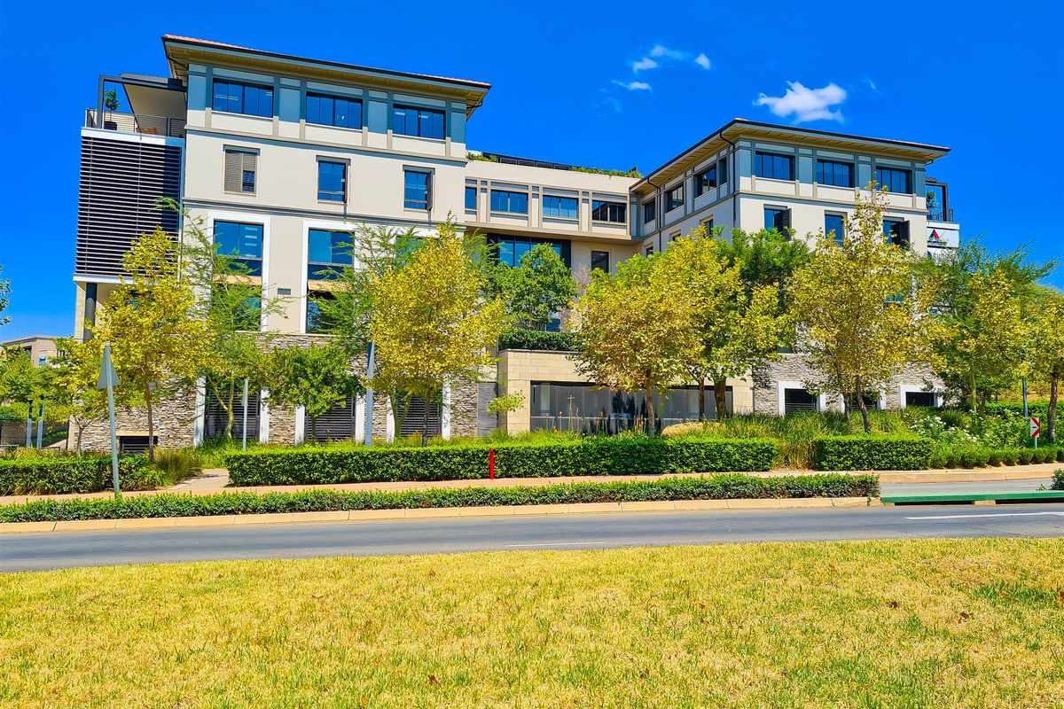 A modern multi-story office building featuring stone cladding, large glass windows, and well-maintained landscaped surroundings.