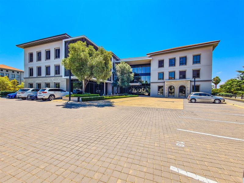 A professional multi-story office building featuring a paved parking area, modern glass facade, and well-maintained exterior landscaping.