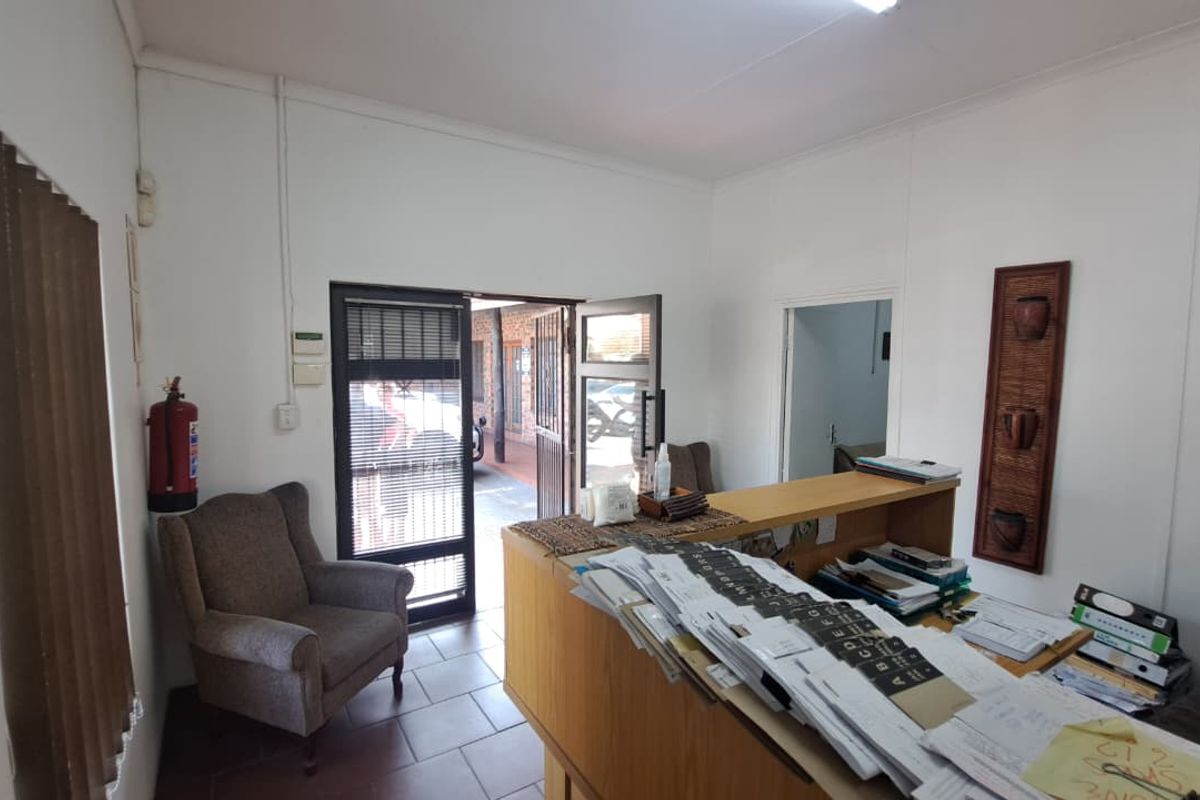 A functional office reception area featuring a built-in counter, tiled flooring, and direct access to an exterior walkway.