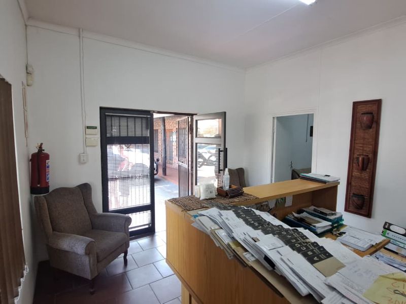 A functional office reception area featuring a built-in counter, tiled flooring, and direct access to an exterior walkway.