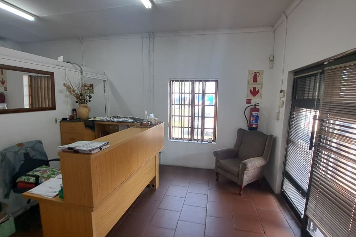 A functional office reception area featuring tiled flooring, security window bars, and a built-in reception counter, suitable for professional business operations.