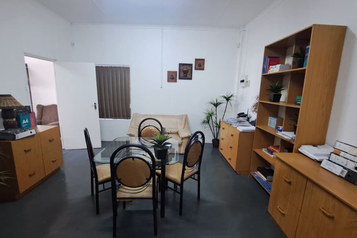 A functional office space featuring painted concrete flooring and vertical window blinds, providing a practical environment for professional use.