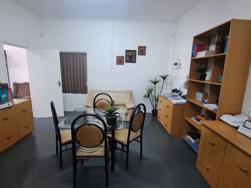 A functional office space featuring painted concrete flooring and vertical window blinds, providing a practical environment for professional use.