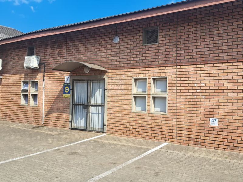Industrial unit exterior featuring face brick facade, security gates, and dedicated paved parking bays with wall-mounted air conditioning units.