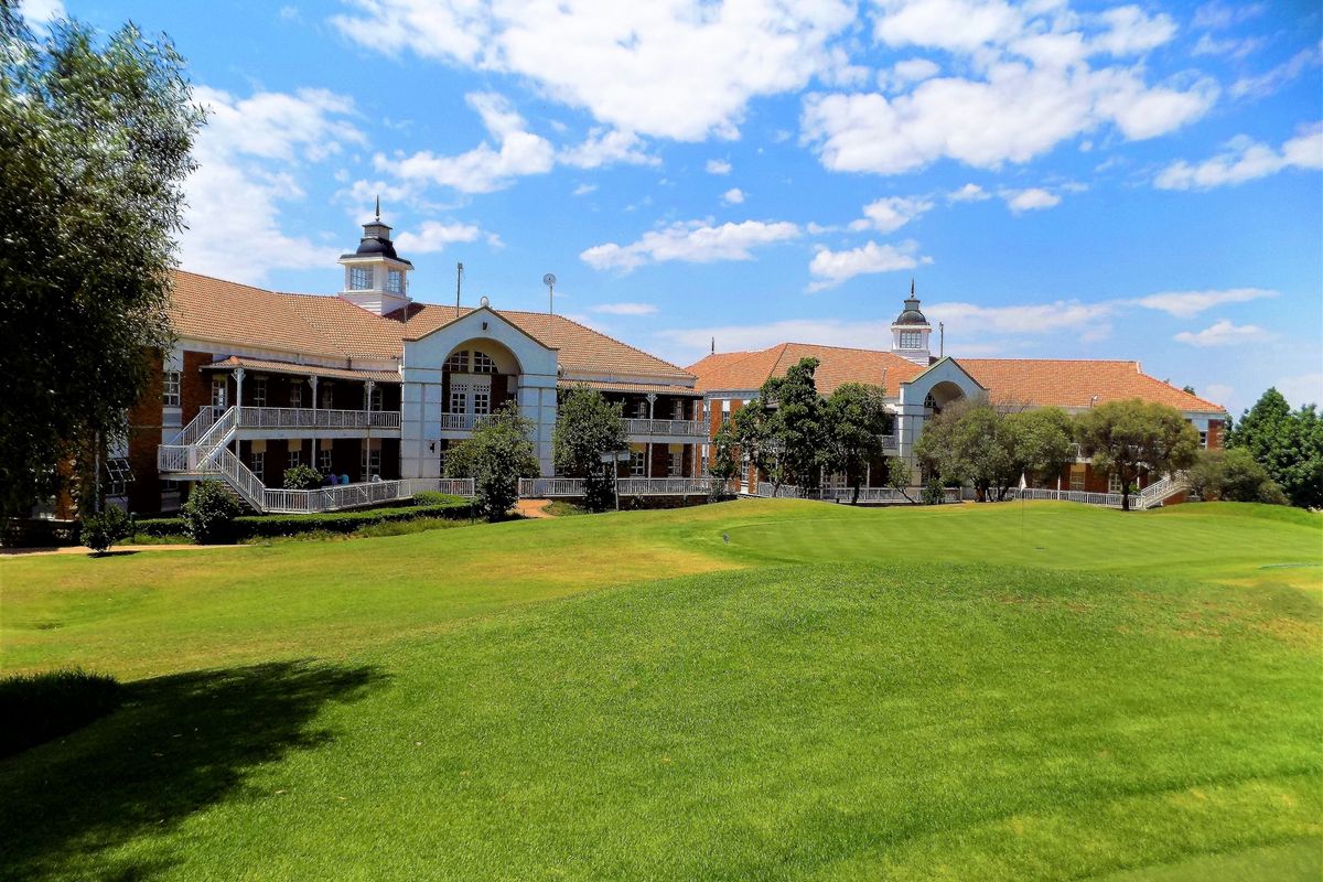 A view of the rear elevation of a large office complex featuring classic architectural details, multi-level balconies, and well-maintained surrounding lawns.