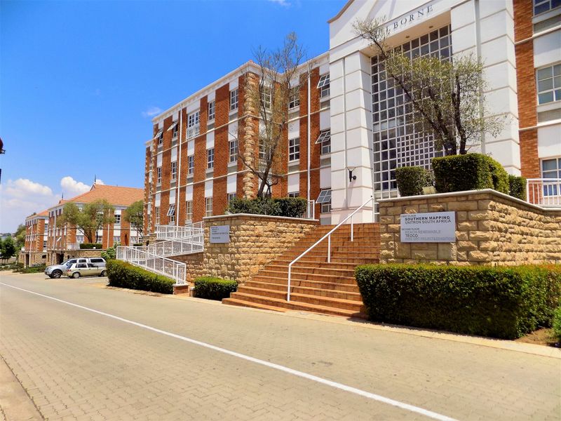 Front elevation of a multi-story office building featuring brick and stone facade, accessible ramp, and paved entrance staircase.
