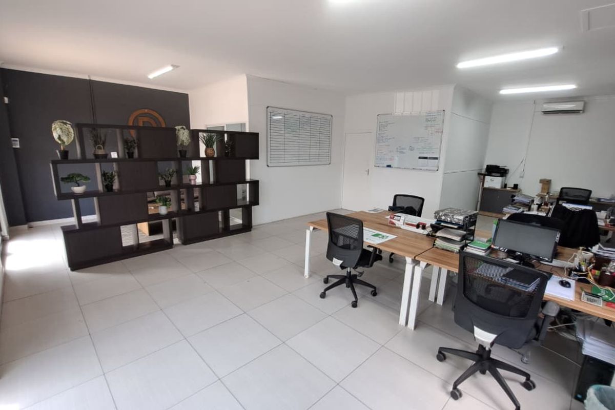 A functional open-plan office space featuring tiled flooring, integrated air conditioning, and wall-mounted whiteboards, suitable for a professional work environment.