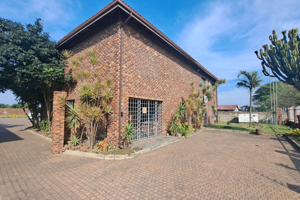 Exterior view of a face brick industrial building featuring a paved driveway and secure window grilles.