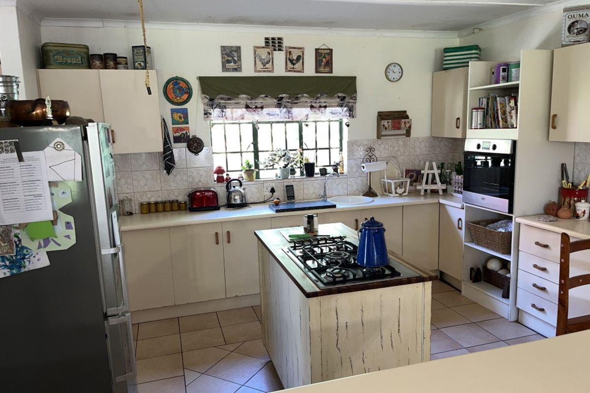 A functional kitchen featuring a central island with a built-in gas hob, tiled backsplash, and ample cabinetry for storage.