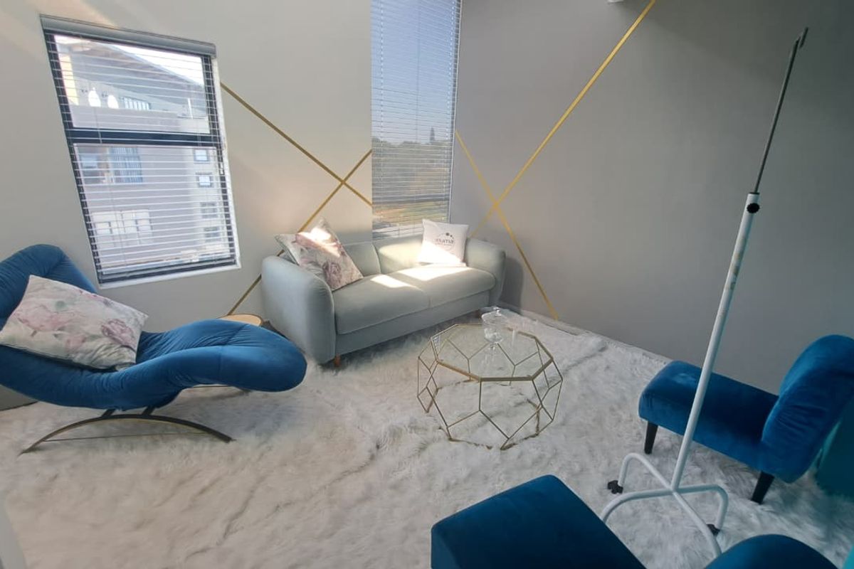 A modern office space featuring clean lines, neutral walls with gold accent detailing, and large windows with fitted venetian blinds.