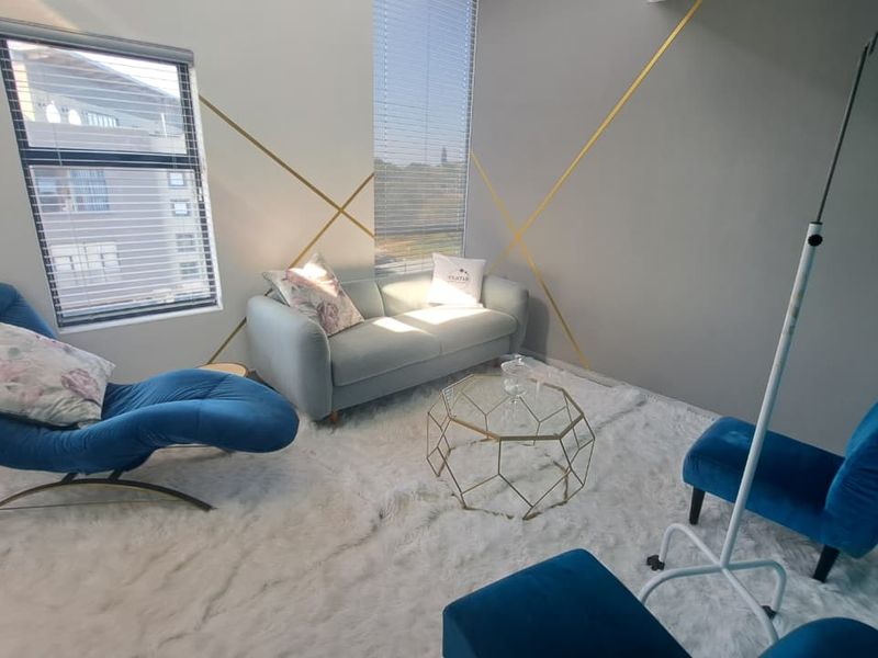 A modern office space featuring clean lines, neutral walls with gold accent detailing, and large windows with fitted venetian blinds.