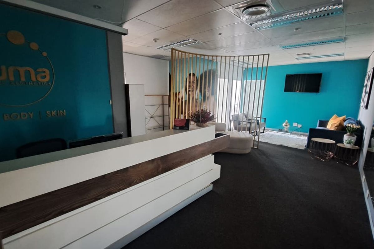 A professional office reception area featuring a modern built-in desk, suspended ceiling with recessed lighting, and a clean, branded aesthetic.