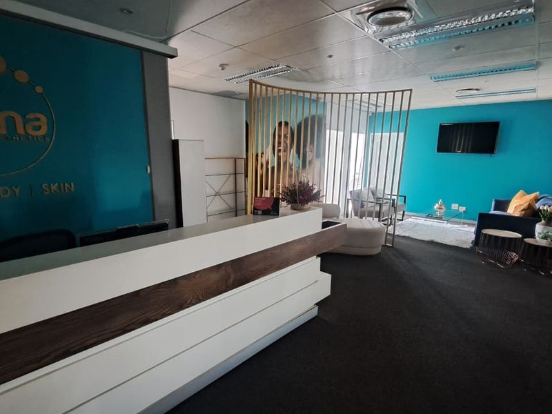 A professional office reception area featuring a modern built-in desk, suspended ceiling with recessed lighting, and a clean, branded aesthetic.