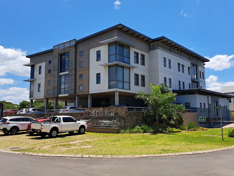 A modern multi-story office building featuring stone cladding, glass facade elements, and an integrated parking area with landscaped surroundings.