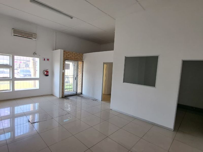 Open-plan industrial office space featuring tiled flooring, split-system air conditioning, and neutral white walls, suitable for a variety of commercial uses.