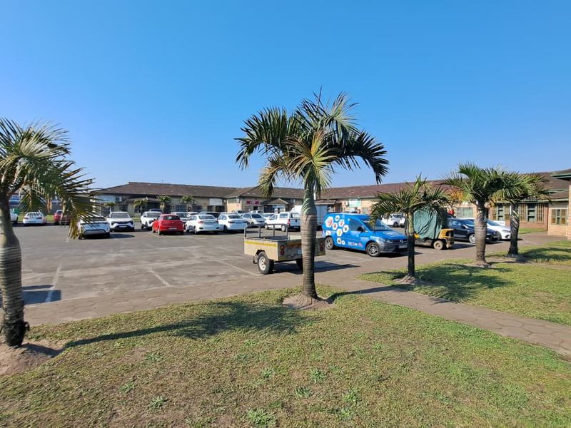 Exterior view of an industrial property featuring a paved parking lot, landscaped palm trees, and brick building facades.