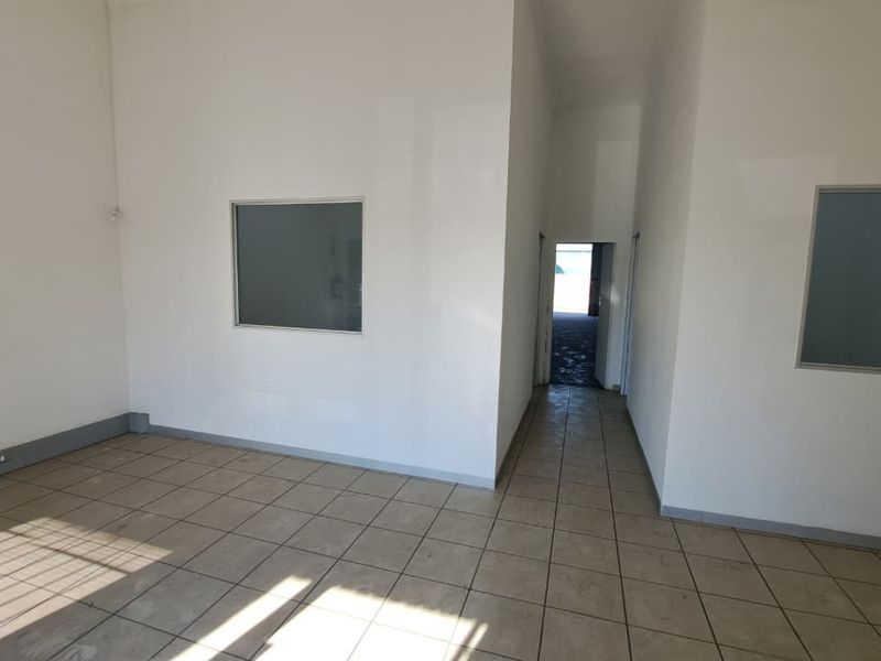 An empty, open-plan office space featuring neutral tiled flooring, white walls, and internal glass partition windows, offering a clean and versatile workspace.