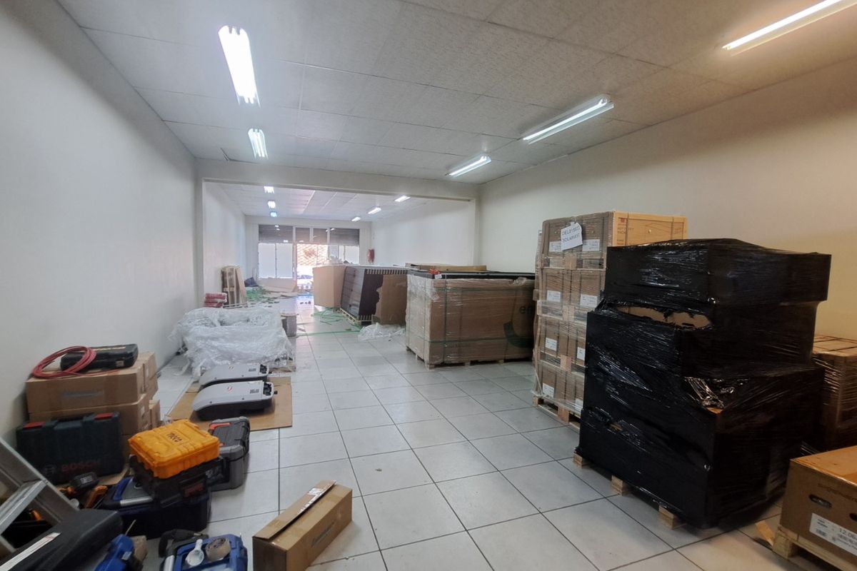 A functional retail utility or storage space featuring tiled flooring and suspended ceiling lighting, currently utilized for inventory storage.