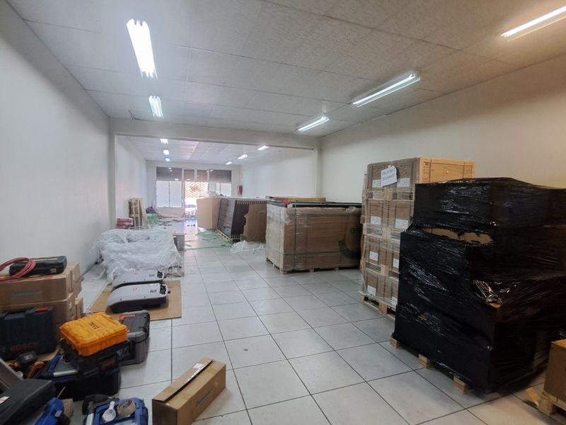 A functional retail utility or storage space featuring tiled flooring and suspended ceiling lighting, currently utilized for inventory storage.