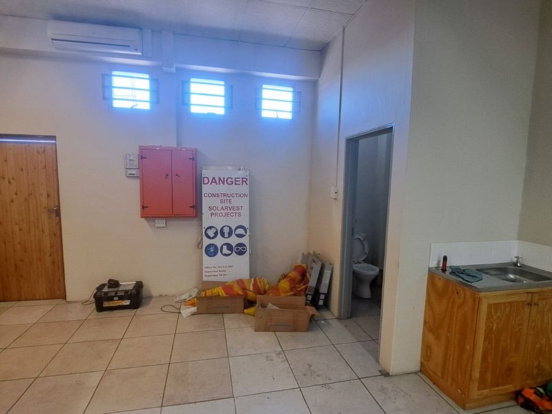 A functional utility space featuring tiled flooring, a built-in sink cabinet, air conditioning, and direct access to a private restroom facility.