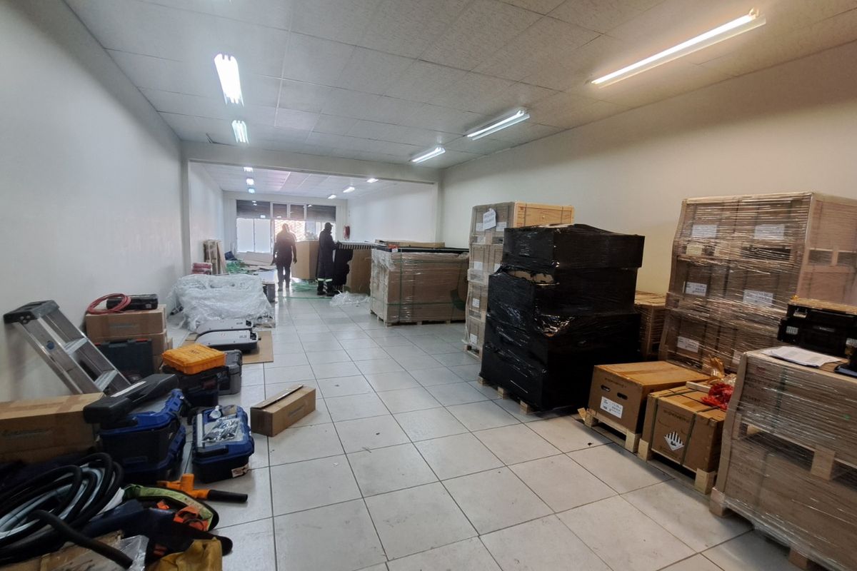 A functional retail utility or storage space featuring tiled flooring, suspended ceiling, and integrated fluorescent lighting, currently used for inventory storage.