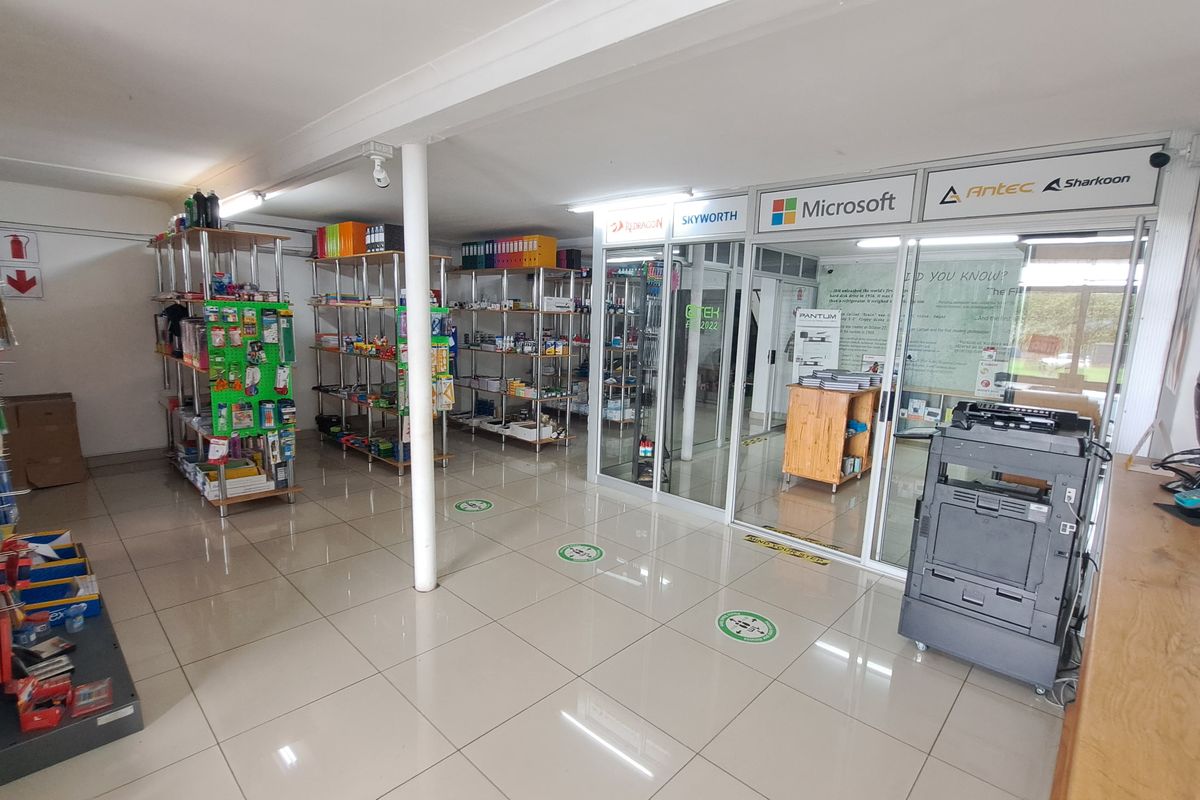 Commercial office space featuring tiled flooring, glass partitioned offices, and open shelving units for retail or administrative use.