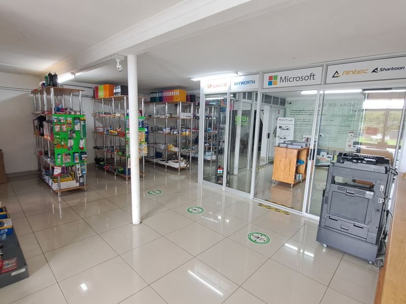 Commercial office space featuring tiled flooring, glass partitioned offices, and open shelving units for retail or administrative use.