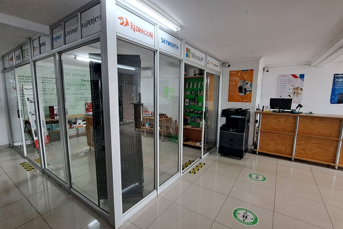 Commercial office space featuring aluminium and glass partitioning, tiled flooring, and a built-in reception counter in a professional retail or business environment.