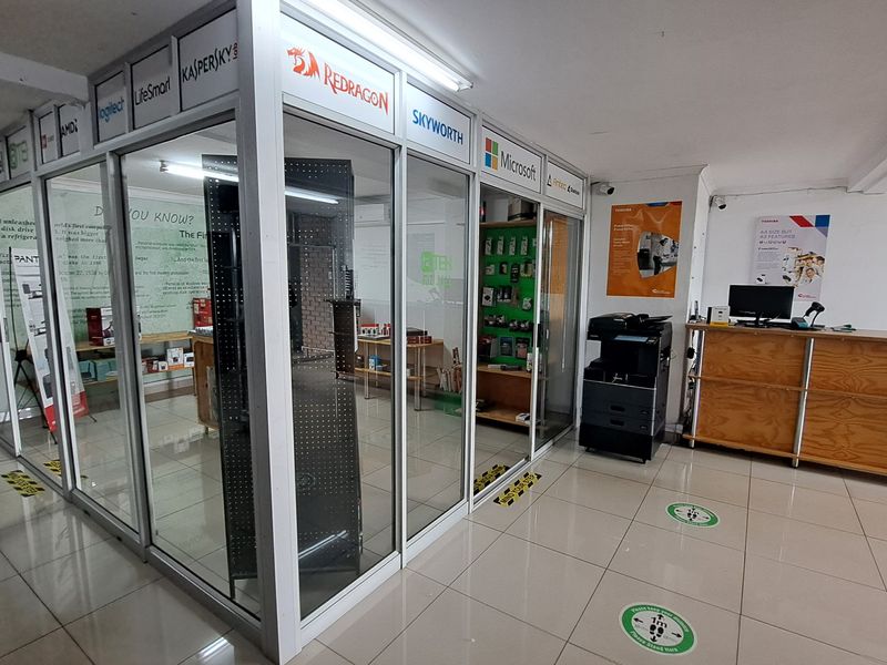 Commercial office space featuring aluminium and glass partitioning, tiled flooring, and a built-in reception counter in a professional retail or business environment.