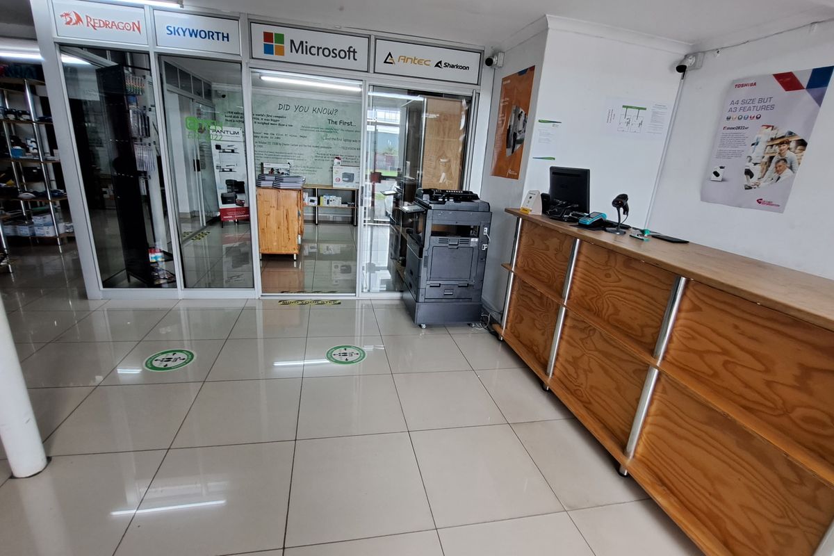 Commercial office entrance featuring a built-in wooden reception counter, tiled flooring, and glass partition walls leading to an inner office area.