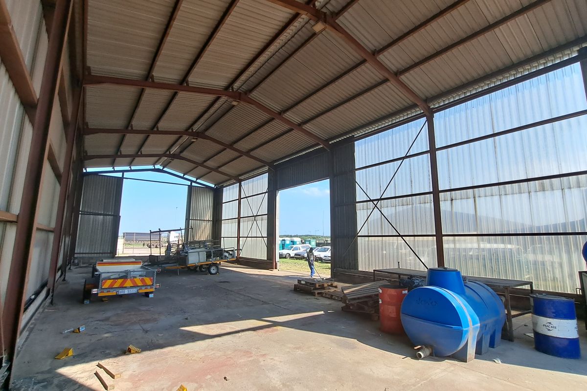 Spacious industrial warehouse or utility shed featuring a steel portal frame, concrete flooring, and translucent roof panels for natural lighting.