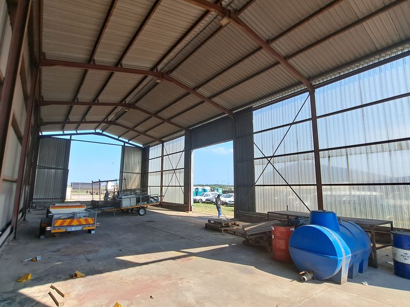 Spacious industrial warehouse or utility shed featuring a steel portal frame, concrete flooring, and translucent roof panels for natural lighting.