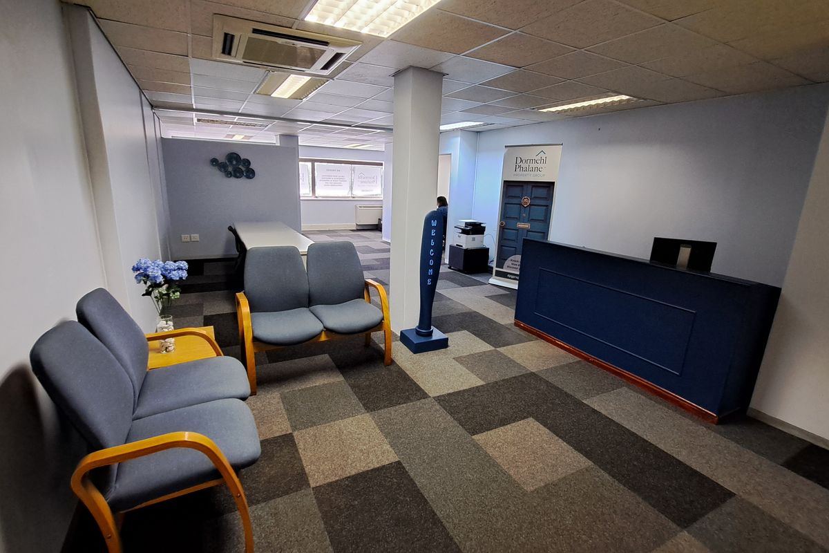 A professional office reception area featuring carpet tiles, a built-in reception desk, and integrated ceiling lighting with central air conditioning.
