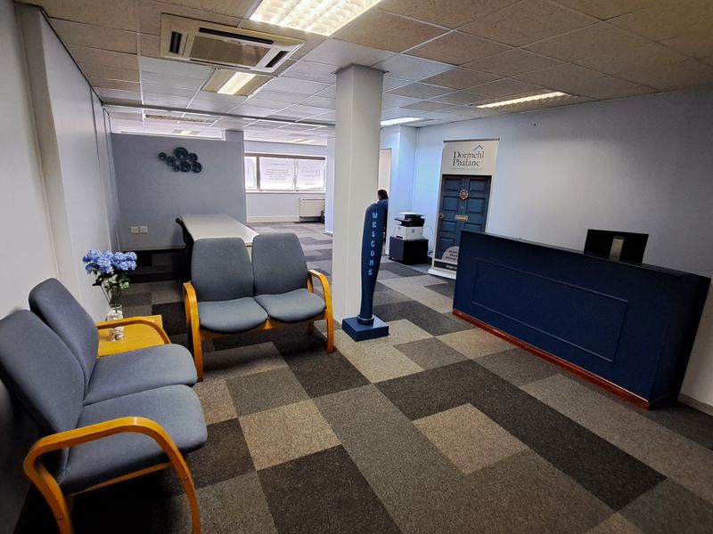 A professional office reception area featuring carpet tiles, a built-in reception desk, and integrated ceiling lighting with central air conditioning.