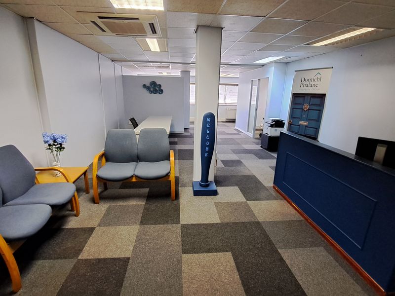 Professional office reception area featuring a built-in reception desk, carpeted flooring, and a suspended ceiling with integrated lighting.