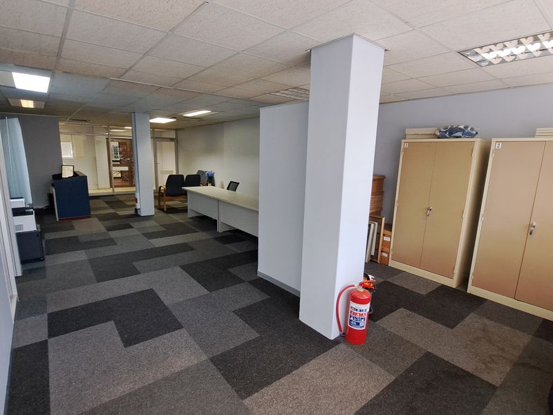 Open-plan office space featuring suspended ceilings, recessed lighting, and durable carpet tiles, providing a functional workspace with integrated storage cupboards.