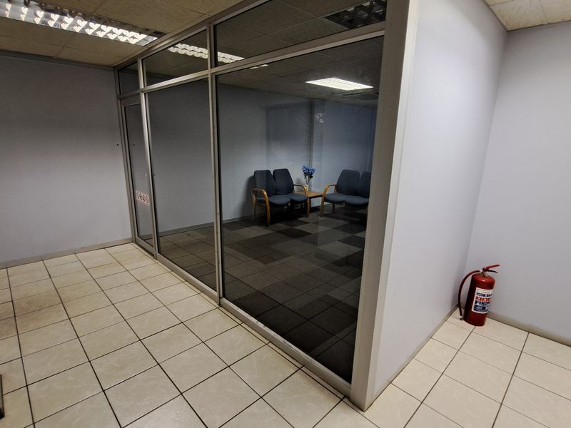 A partitioned office space featuring glass walls, suspended ceilings with recessed lighting, and a combination of ceramic and carpeted flooring.