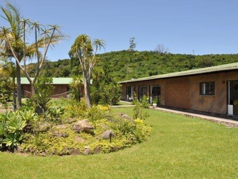 A view of the rear exterior of the farm property, featuring a well-maintained lawn, landscaped garden beds, and sliding glass door access.