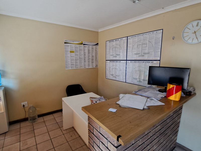 A functional office space featuring a brick-faced reception counter and tiled flooring, suitable for administrative or industrial reception use.
