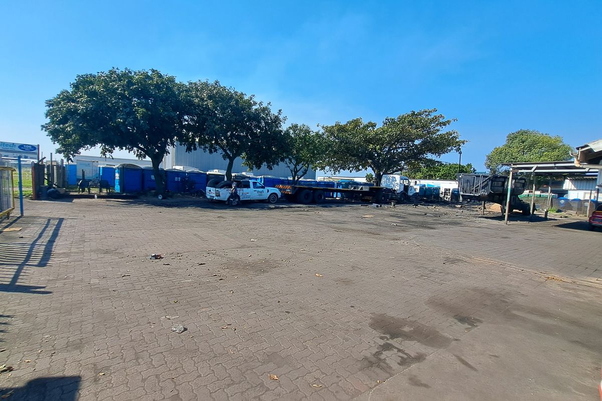 Spacious industrial paved yard area featuring perimeter metal fencing and a covered structure, suitable for vehicle storage or operational use.