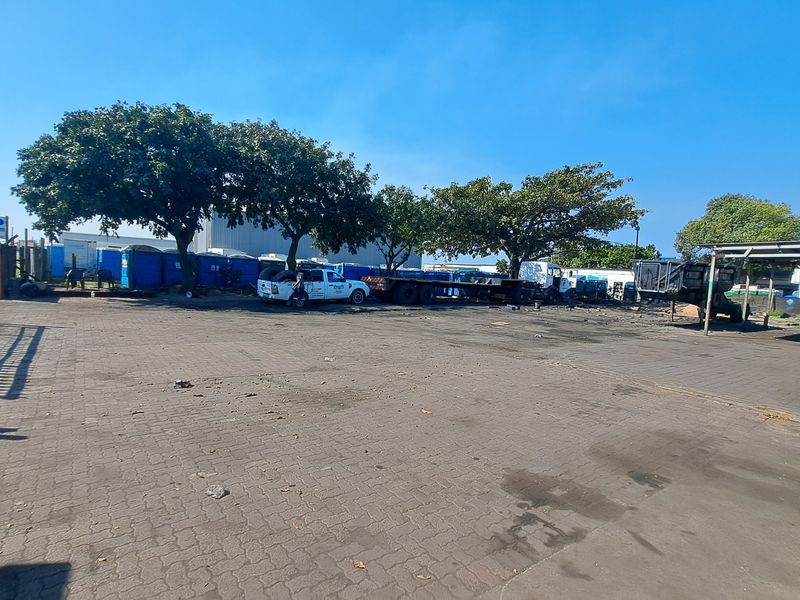 Spacious industrial paved yard area featuring perimeter metal fencing and a covered structure, suitable for vehicle storage or operational use.