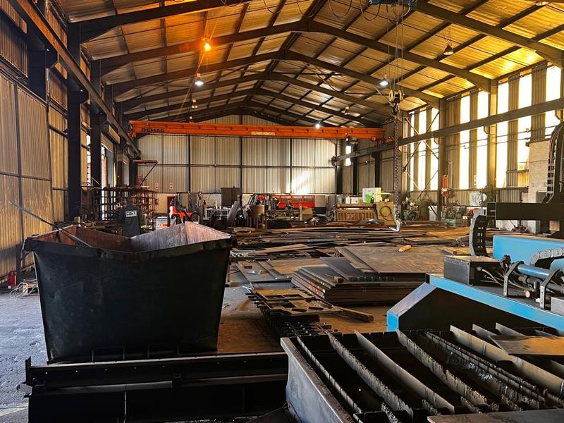 Spacious industrial warehouse featuring a high-clearance steel portal frame, overhead crane system, and durable concrete flooring, suitable for heavy manufacturing or storage operations.