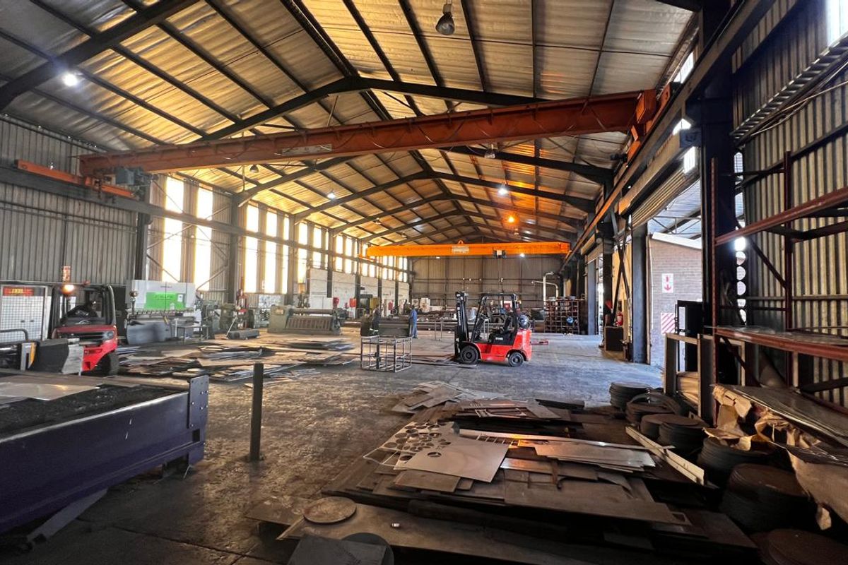 Spacious industrial warehouse featuring a high-clearance steel portal frame, overhead gantry crane, and durable concrete flooring, suitable for heavy manufacturing or storage operations.