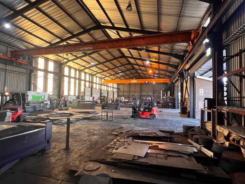 Spacious industrial warehouse featuring a high-clearance steel portal frame, overhead gantry crane, and durable concrete flooring, suitable for heavy manufacturing or storage operations.